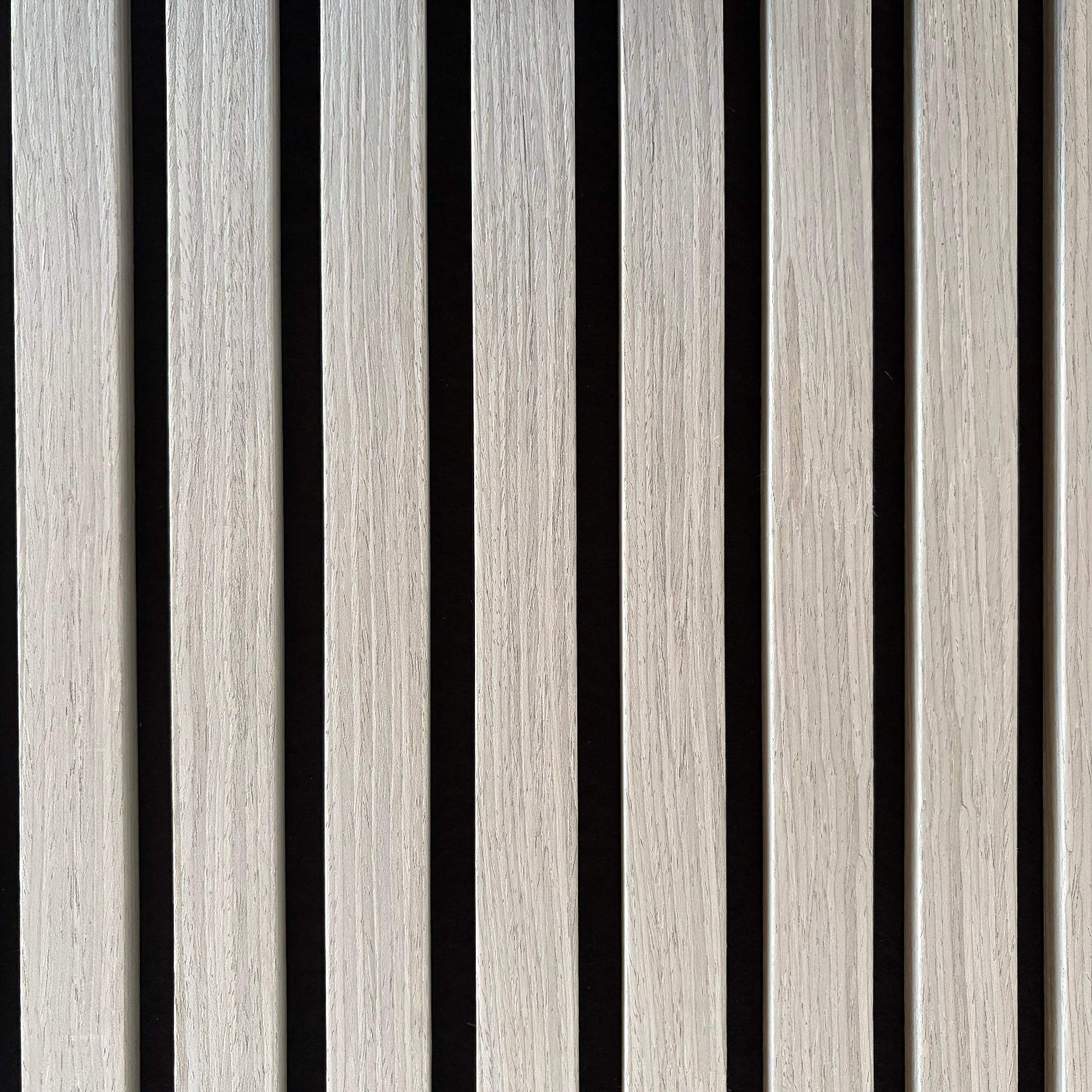 Extreme close-up of Vantaa Grey wood slats, emphasizing natural grain, precise craftsmanship, and sleek gray finish on black background.