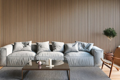 Contemporary living room with Vantaa acoustic panels forming a full warm wood slat wall behind a light blue modular sofa, glass coffee table with candle, potted plant, wooden chair, and gray rug.